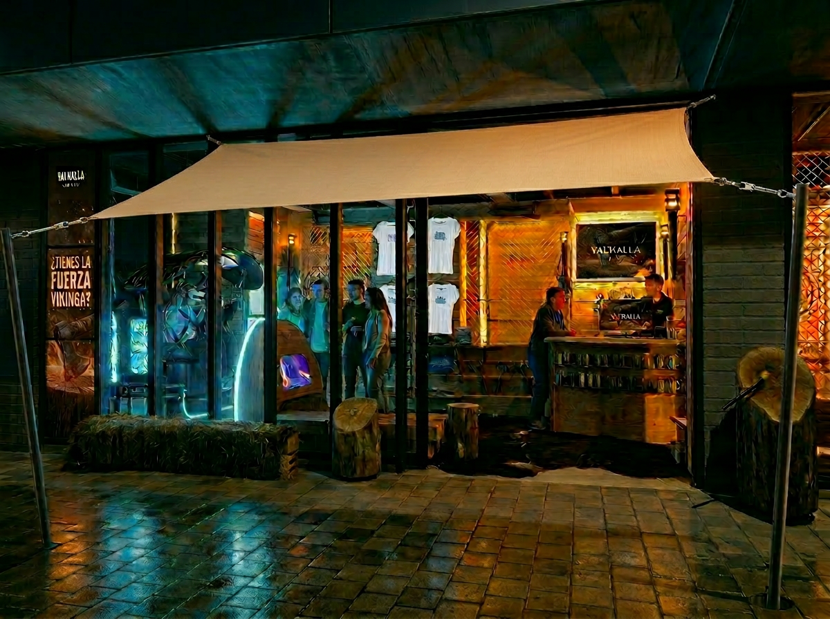 Zona cubierta de juegos al aire libre de Valhalla World iluminada por antorchas y bombillos Edison de noche