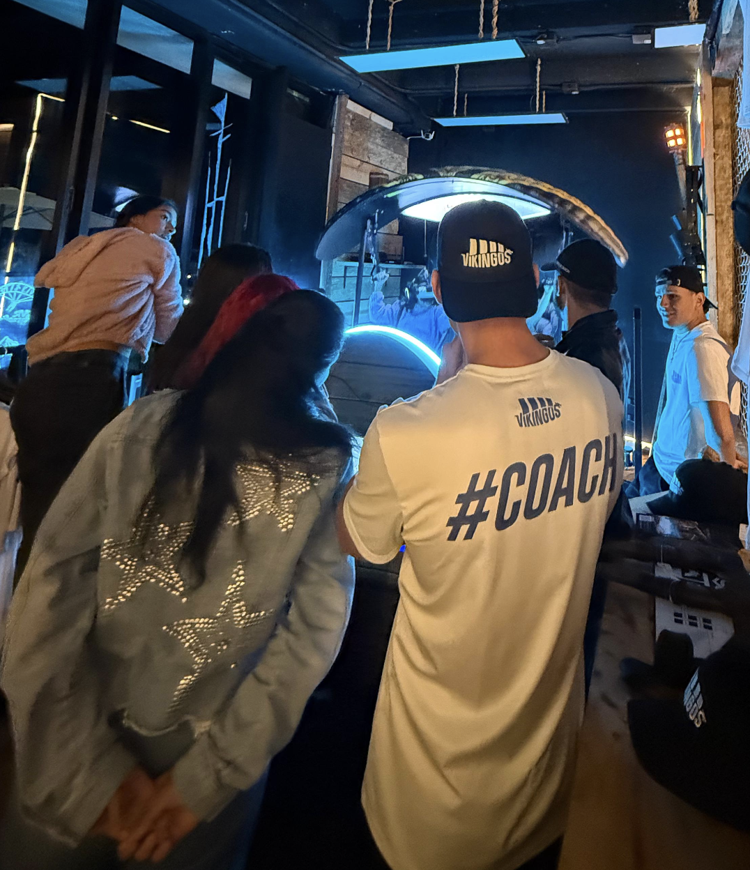 Sala llena en Valhalla World reunida alrededor de la atracción de VR durante un evento grupal